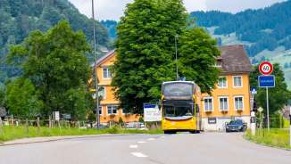 Gelber Doppeldecker-Postbus vor einer grünen Landschaft in Starkenbach