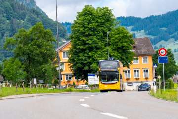 Gelber Doppeldecker-Postbus vor einer grünen Landschaft in Starkenbach